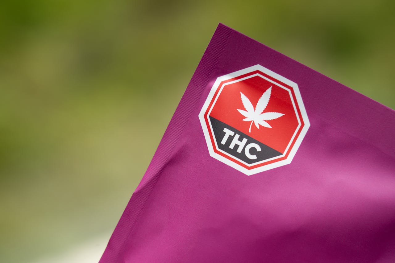 Close-up of cannabis packaging with a THC warning label on a purple background, highlighting safety and regulatory compliance.