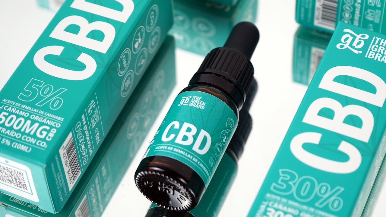 CBD oil and packaging on a reflective surface, highlighting organic hemp product.