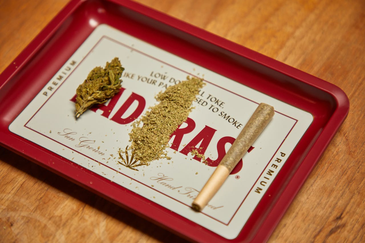 Close-up shot of cannabis, hemp, and a joint on a branded tray, showcasing product packaging.